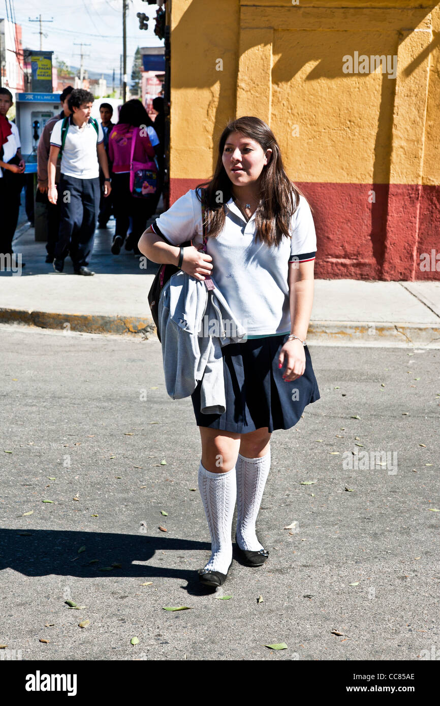 teenage Mexican high school girl wearing uniform with white knee socks crosses street after leaving school Oaxaca Mexico Stock Photo