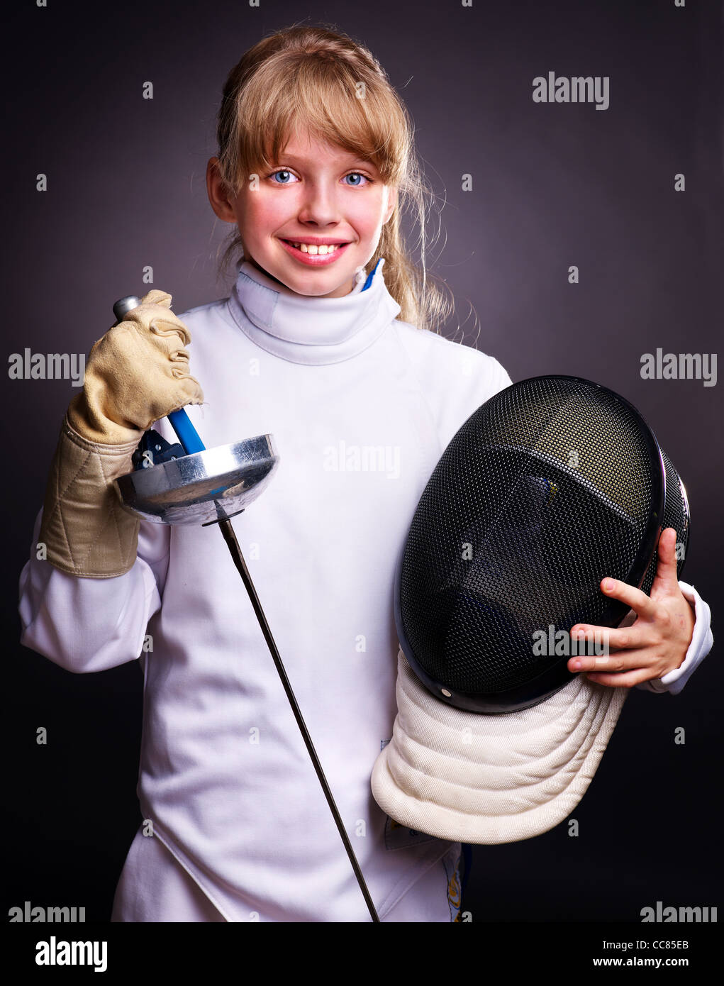 Child in fencing costume holding epee . Black background. Stock Photo