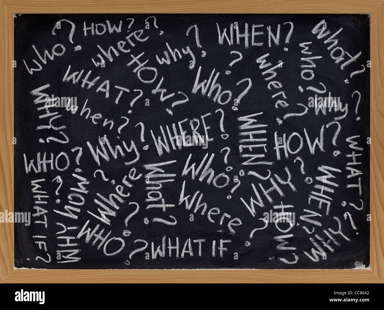 who, what, why, how, where, when, what if questions - white chalk handwriting on blackboard Stock Photo