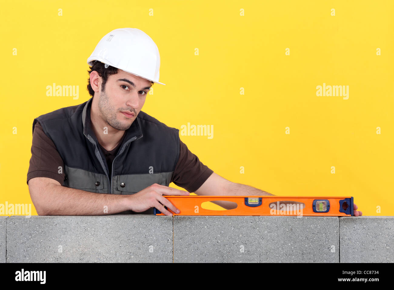 Builder with a spirit level on a wall Stock Photo - Alamy