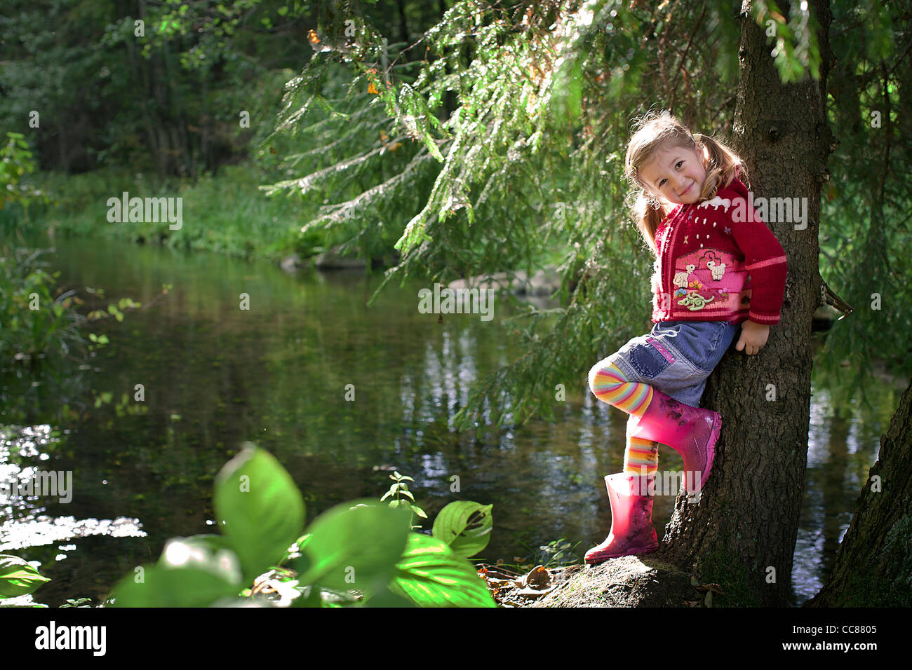 a little smiling girl posing next to the river Stock Photo - Alamy