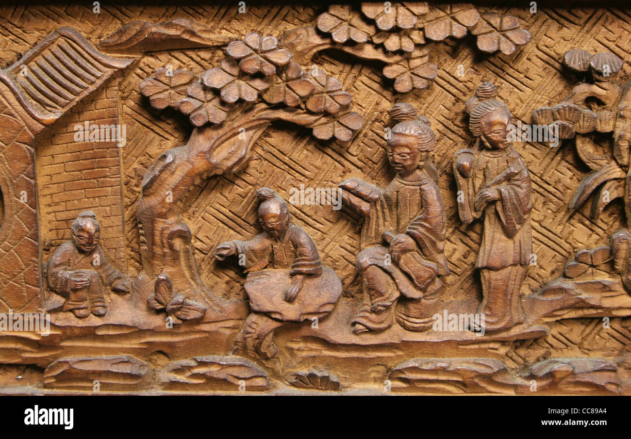 Asian carved wood panel with tree, building, and four people Stock Photo