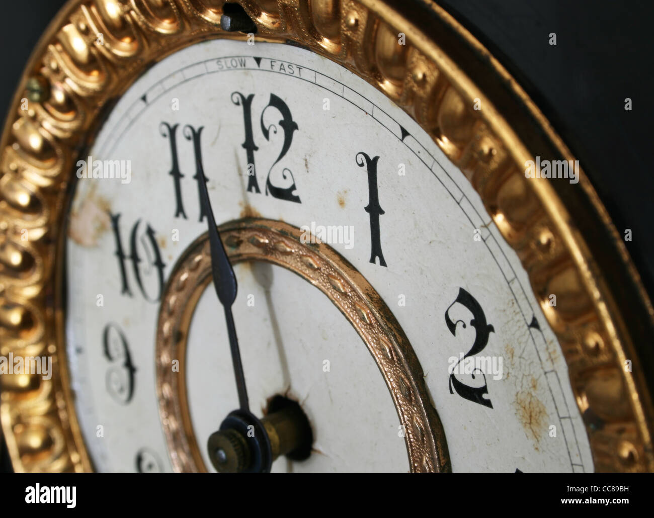 almost 11:30 on an antique clock viewed from an angle with a shallow depth of field Stock Photo
