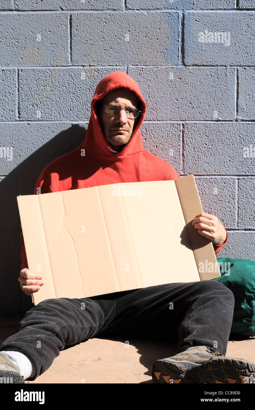 homeless man in red sweatshirt holding a blank cardboard sign Stock Photo