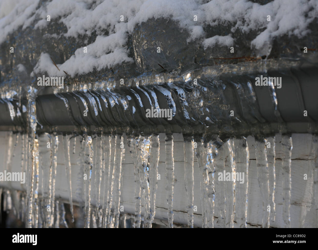 roof ice dam and icicles cover a gutter Stock Photo
