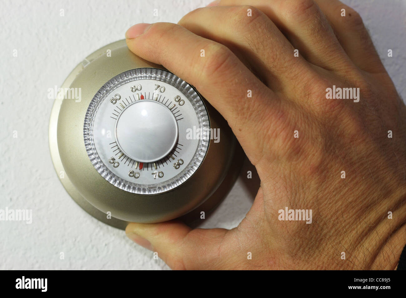 hand setting a thermostat down to 62 degrees Stock Photo