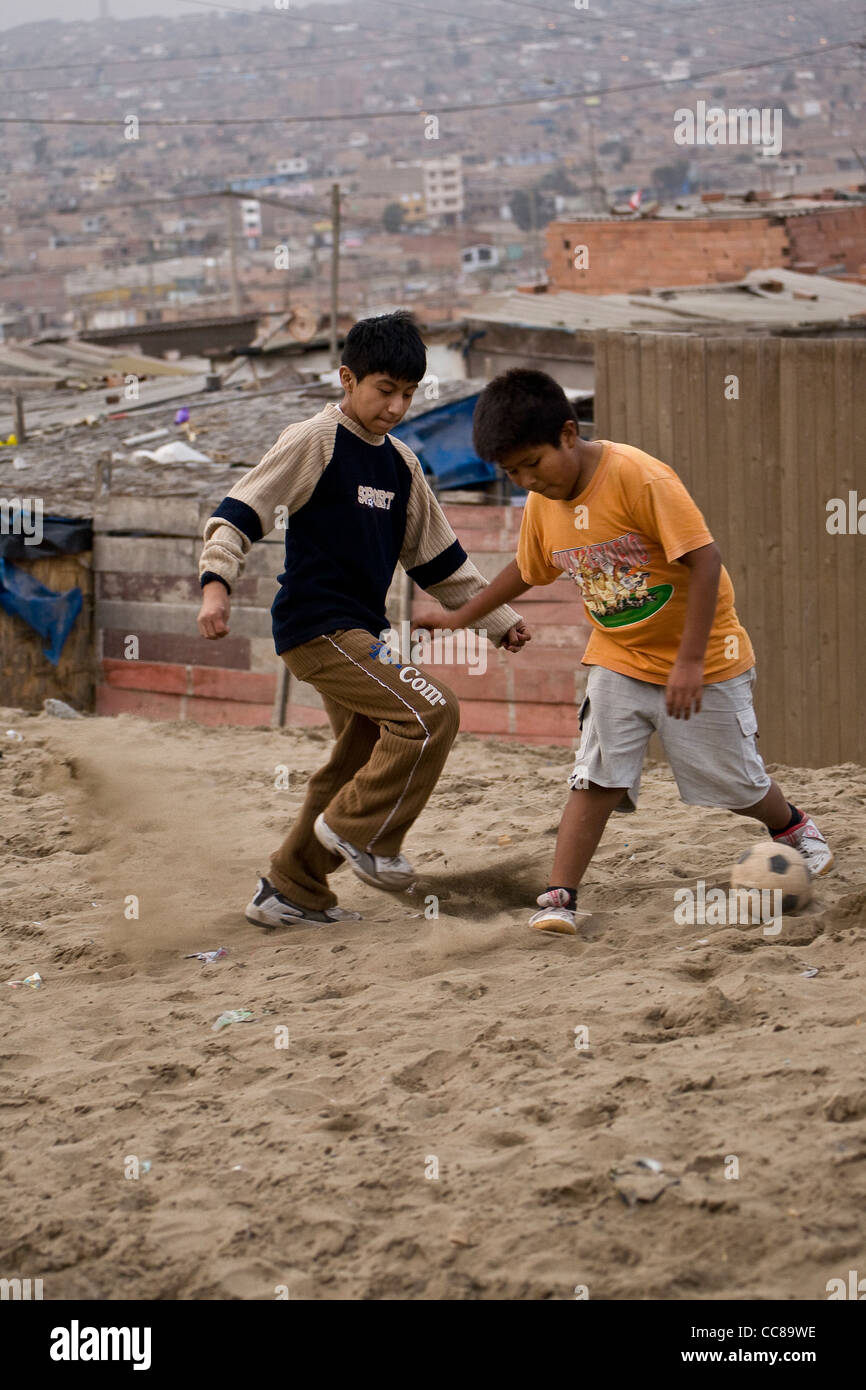 Children play football in the sandy streets of a slum in Lima, Peru, South America. Stock Photo