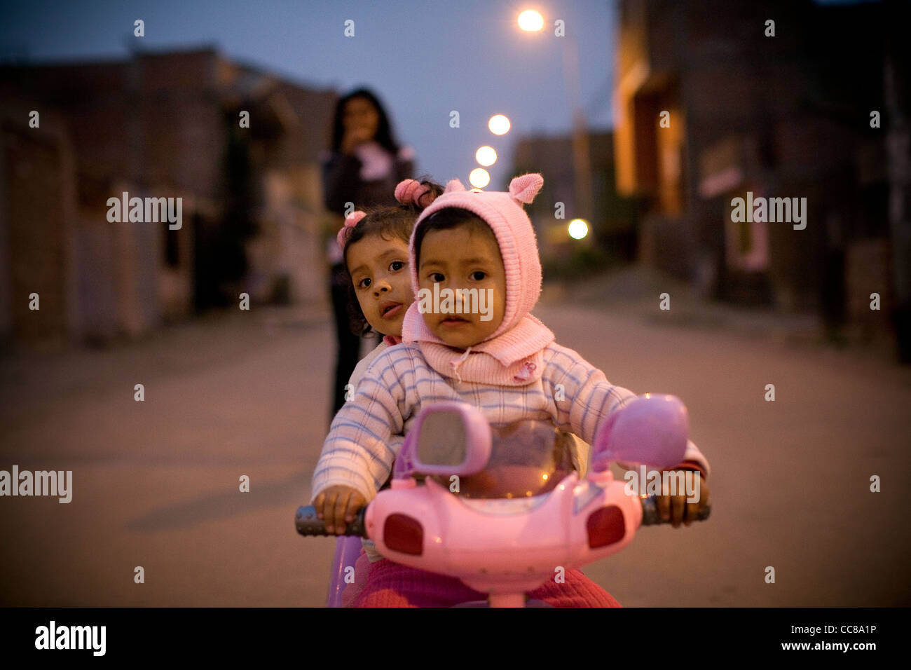Children play on a small bike in Villa el Salvador - Lima, Peru, South America. Stock Photo