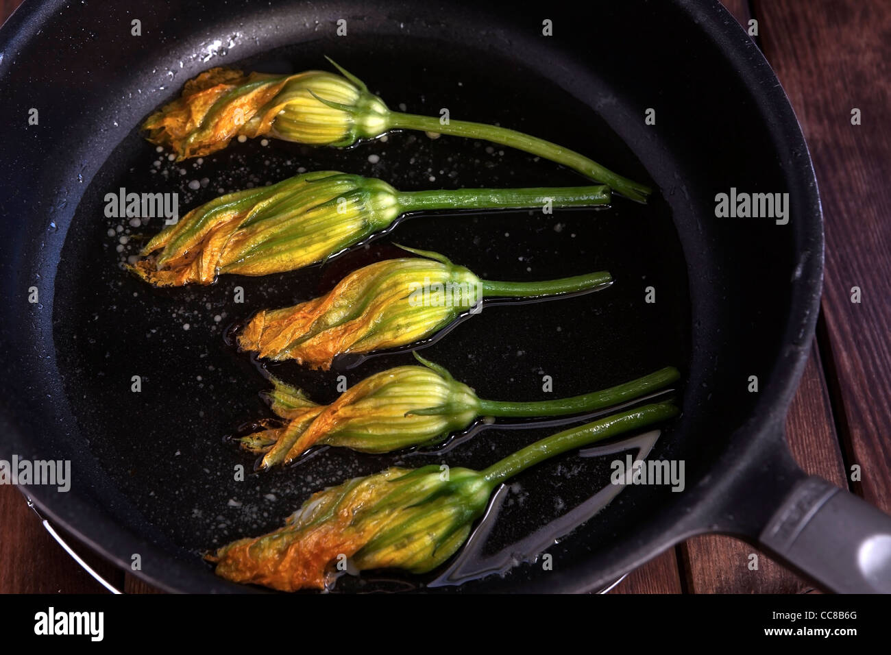 with cottage cheese, chives and tarragon stuffed squash blossoms in a pan with oil to fry Stock Photo