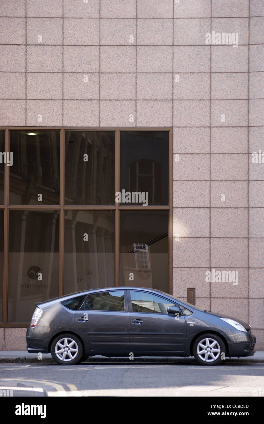 A grey hybrid electric Toyota Prius car in front of a modern building in the City of London, England Stock Photo