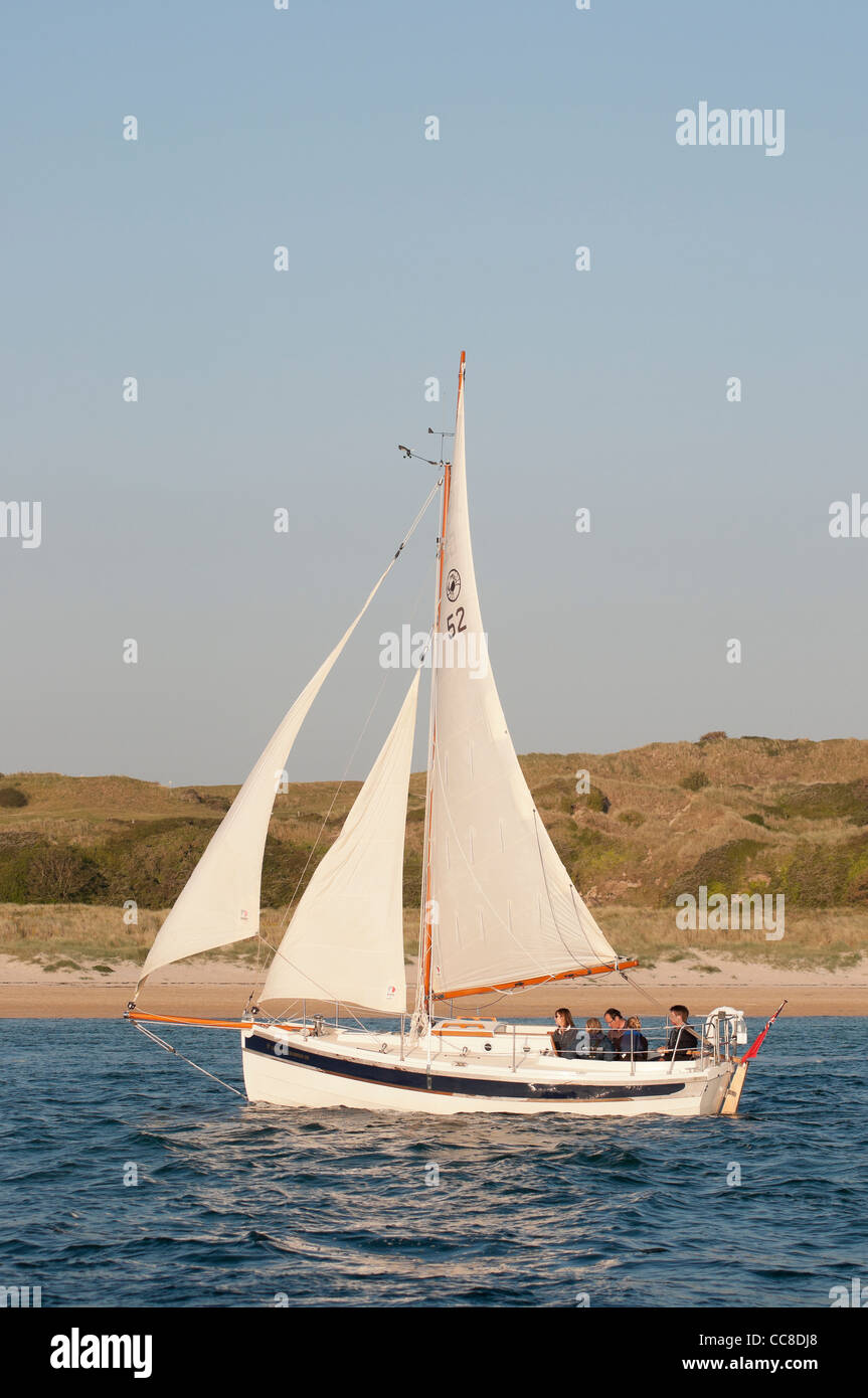 Traditional sailing boat under sail traveling down an estuary Stock Photo