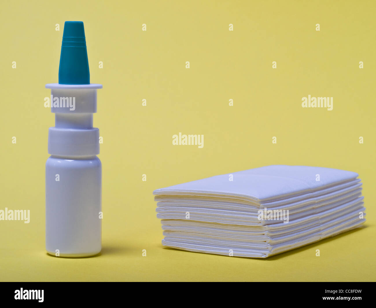 ein Nasenspray, daneben liegen Taschentücher | a nasal spray, beside are handkerchiefs Stock Photo