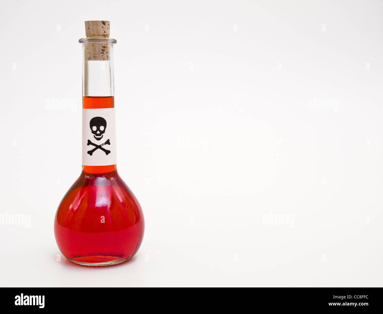 eine Flasche mit roter Flüssigkeit und einem Schild mit einem Totenkopf | a bottle with red liquid and a death's-head label Stock Photo
