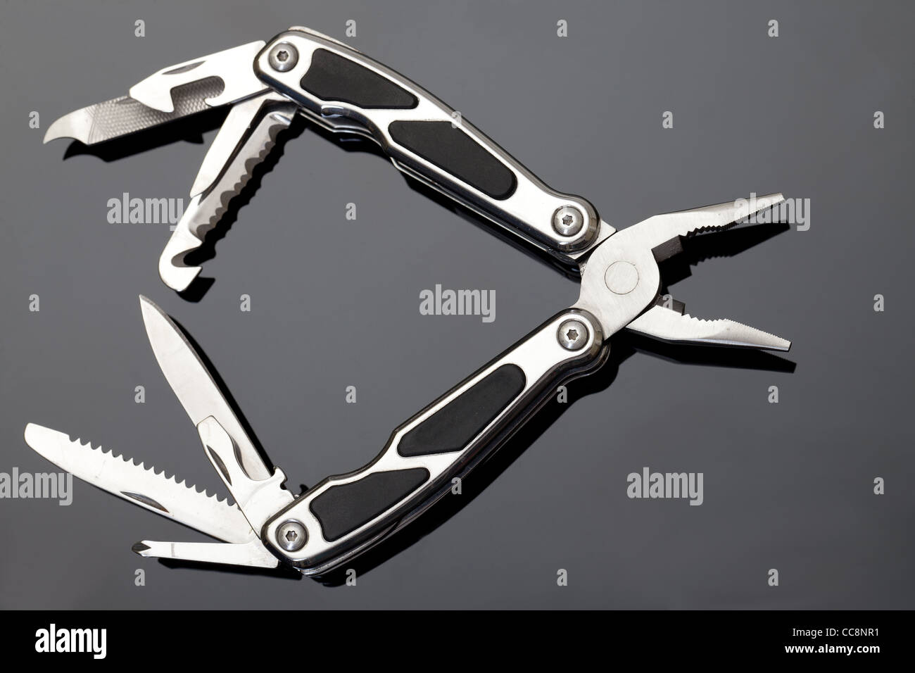 Steel pliers folding multi tool opened on gray background Stock Photo