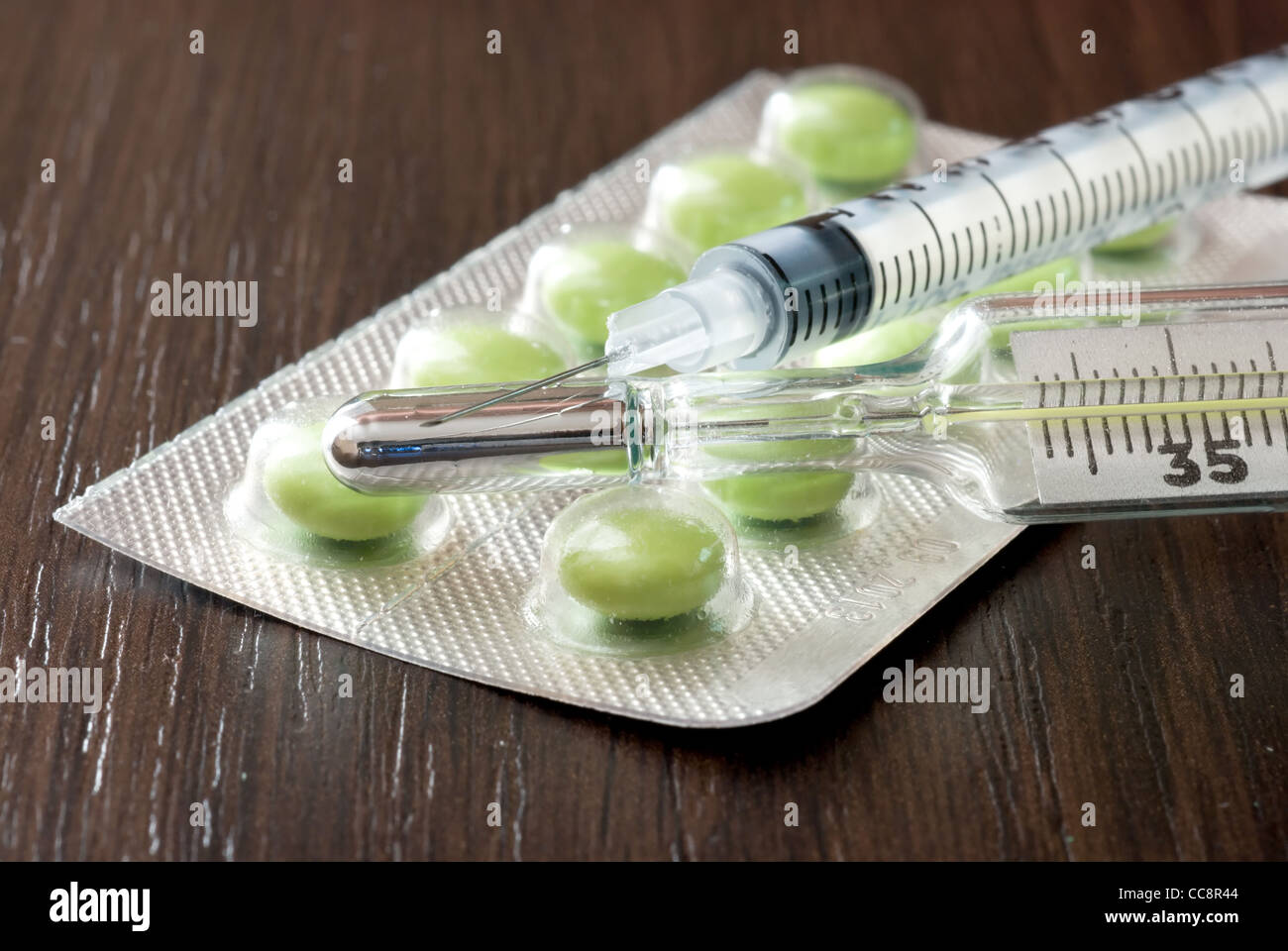 Syringe, pills and a thermometer on the black table Stock Photo