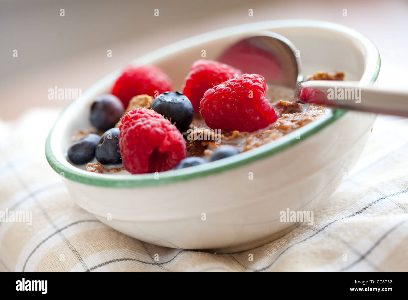Bowl of cereal with raspberries, blueberries and milk for healthy breakfast. Stock Photo