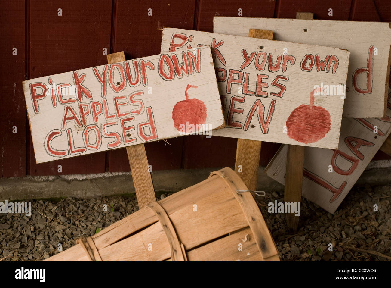 A basket lays on its side with a stack of signs for a pick-your-own apple orchard. Stock Photo