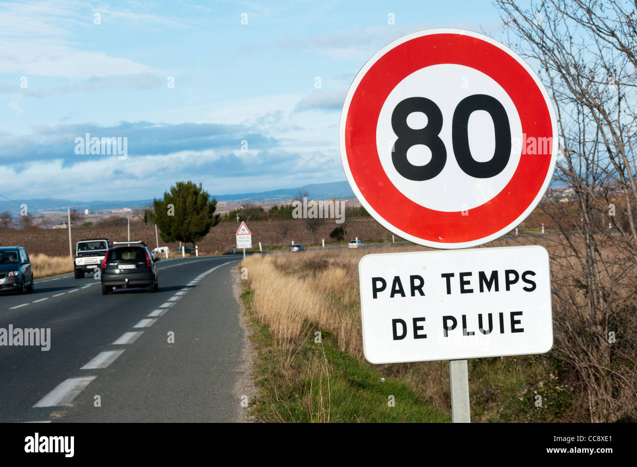 A roadsign on the D909 outside Beziers advises that the speed limit is reduced to 80 km/hour when it is raining. Stock Photo