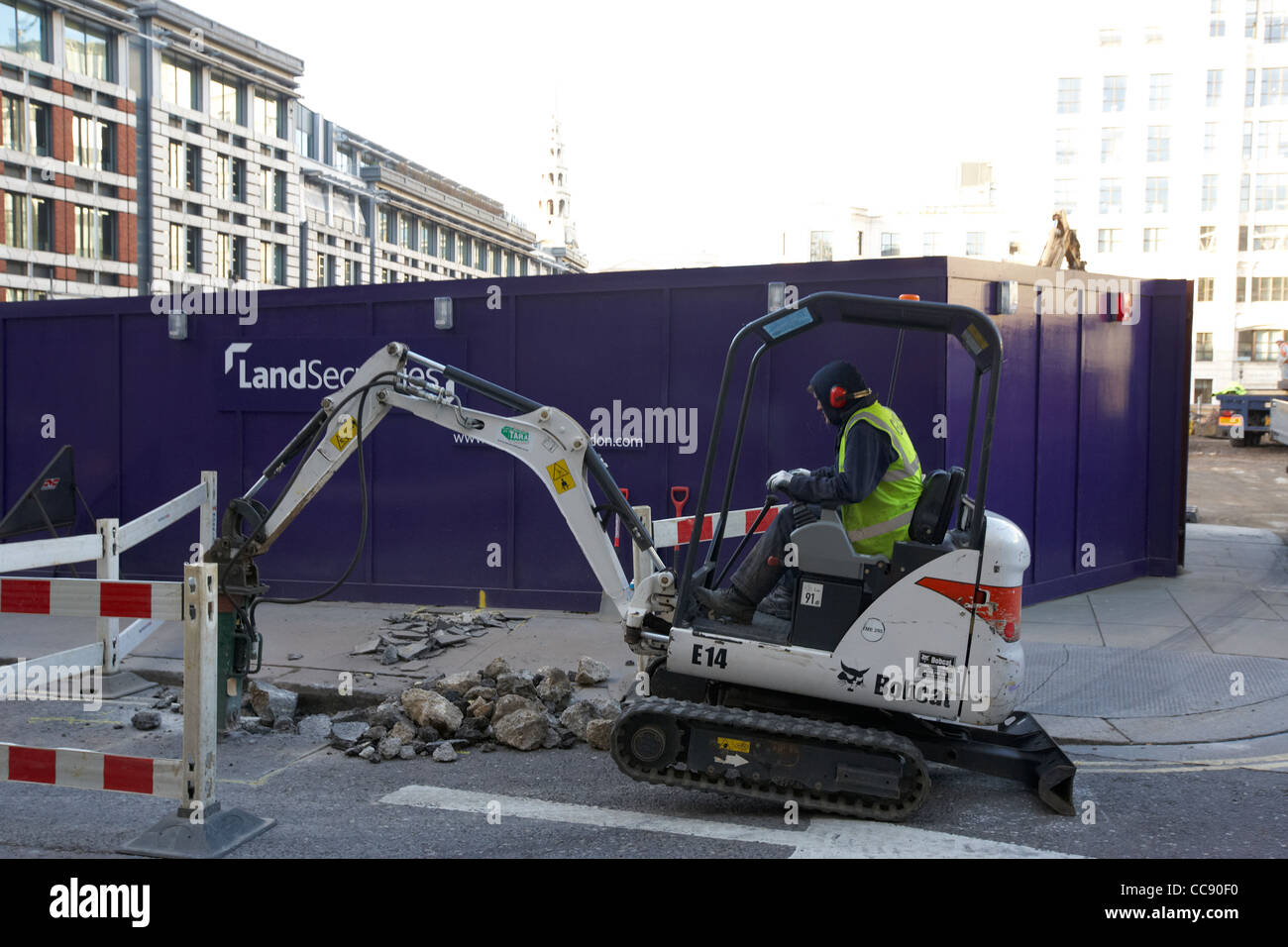 workman using mini bobcat digger digging up city of london streets London England UK United kingdom Stock Photo