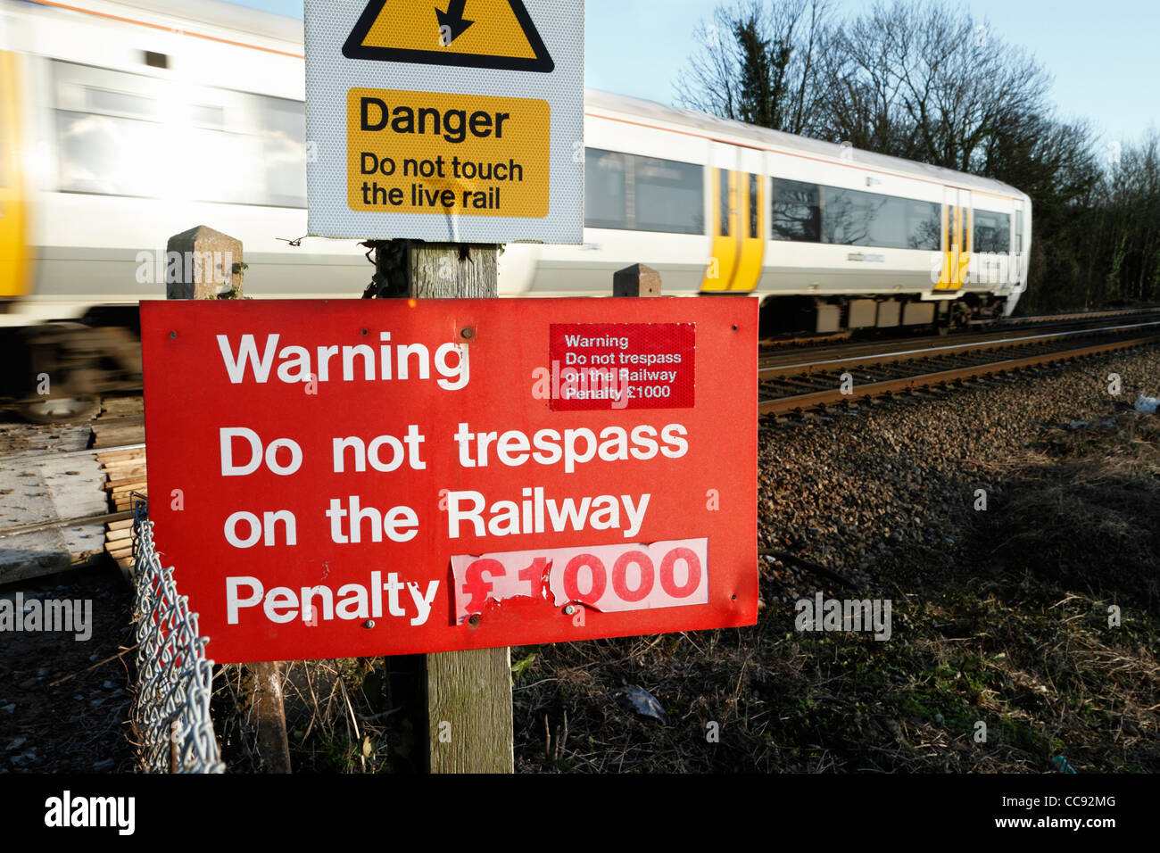 Railway trespass warning sign with passing train Stock Photo