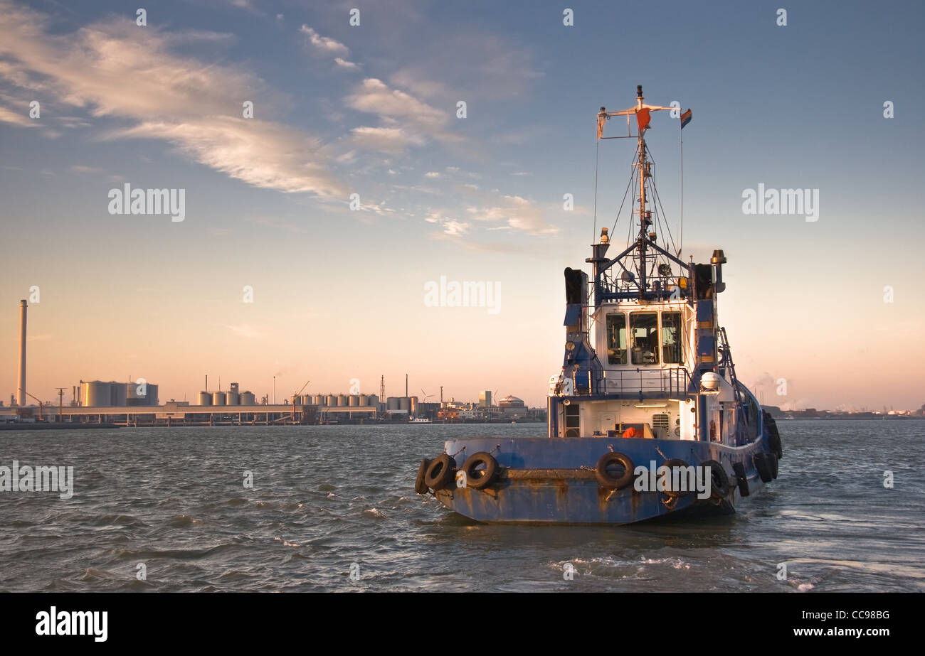 Tugship leaving port at sunrise and sailing down the river Stock Photo