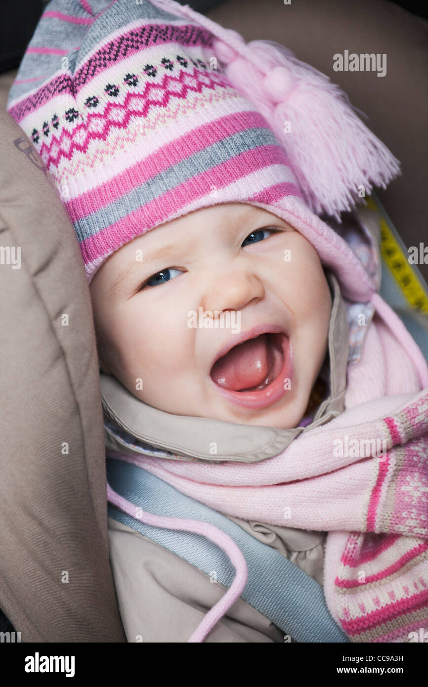 Close-up of Baby Girl Sitting in Car Seat wearing Winter Clothing Stock Photo