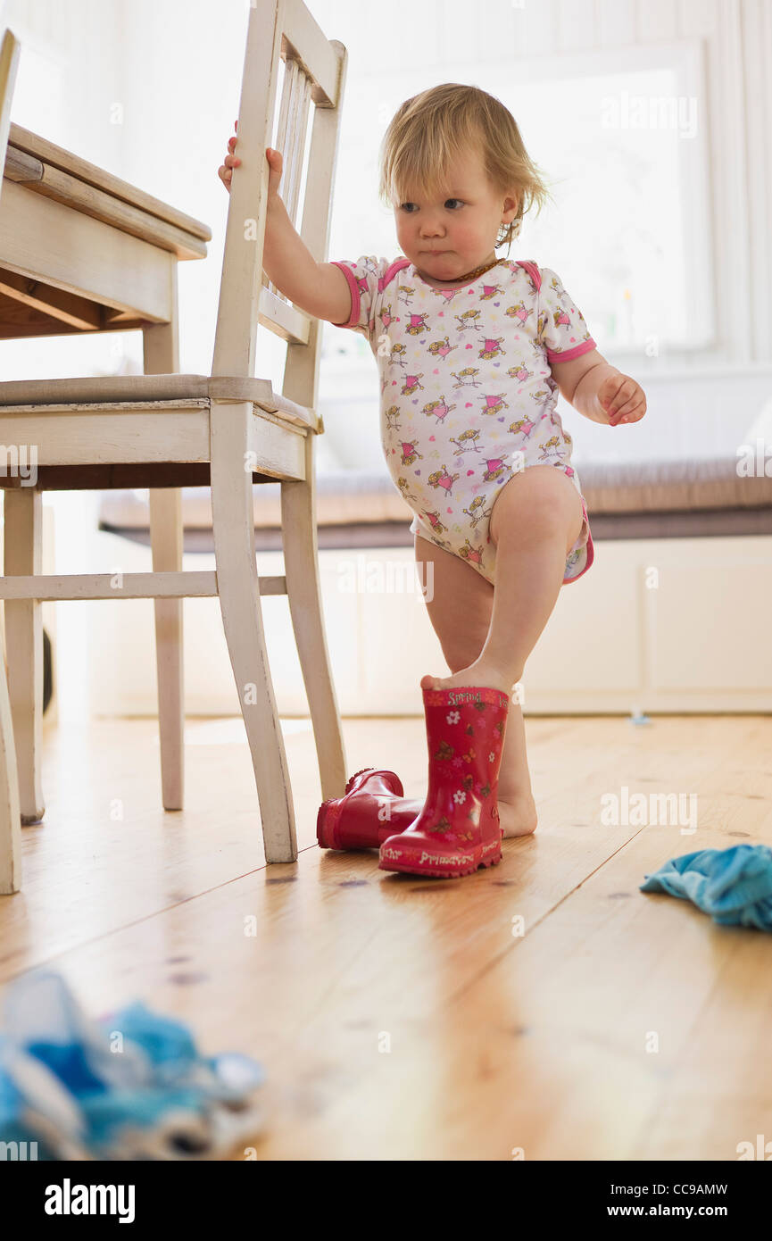 Girl Putting on Rubber Boots Stock Photo