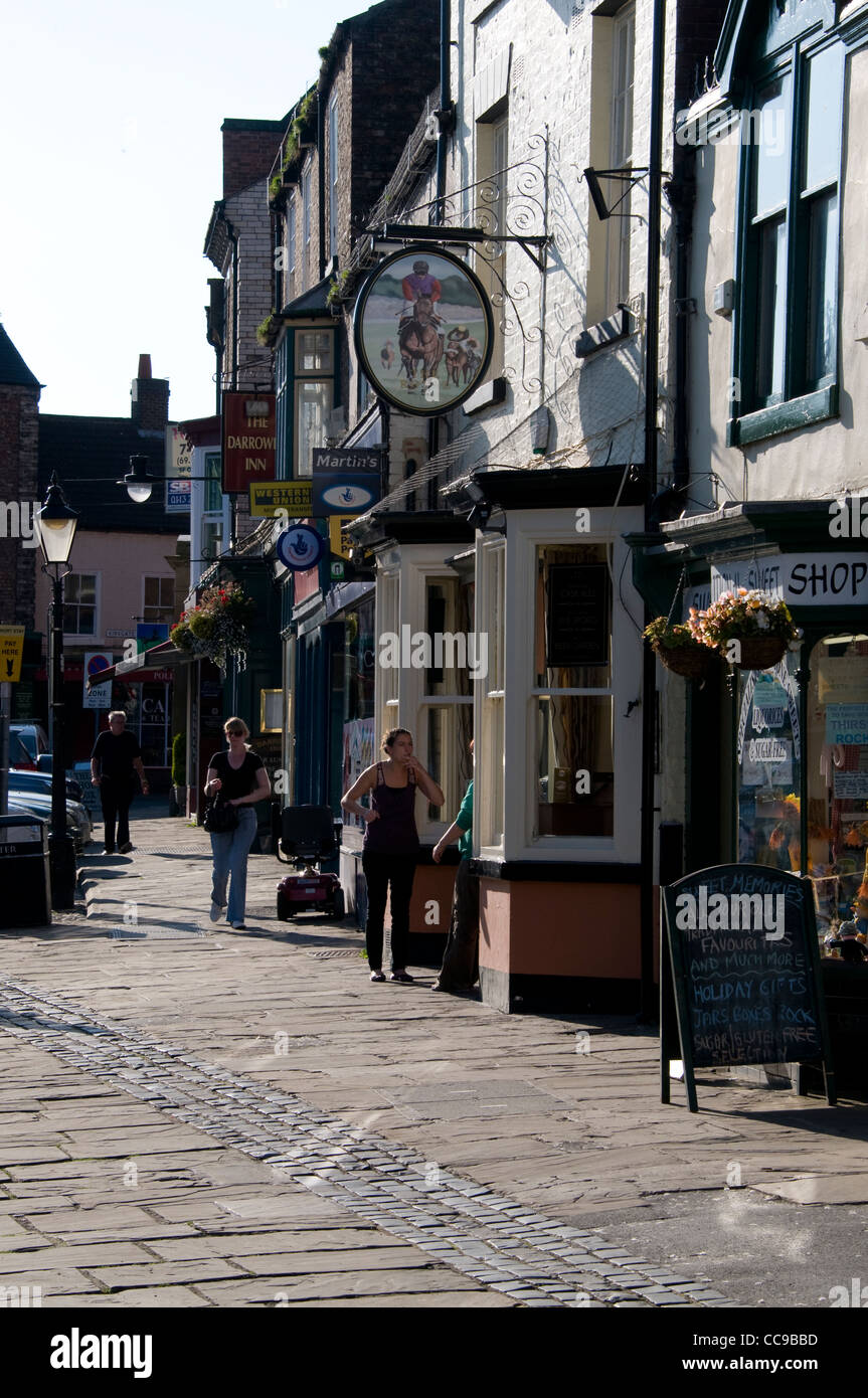 The cobbled Market Place with old fashioned shops in the market town of Thirsk in North Yorkshire, Britain. Stock Photo