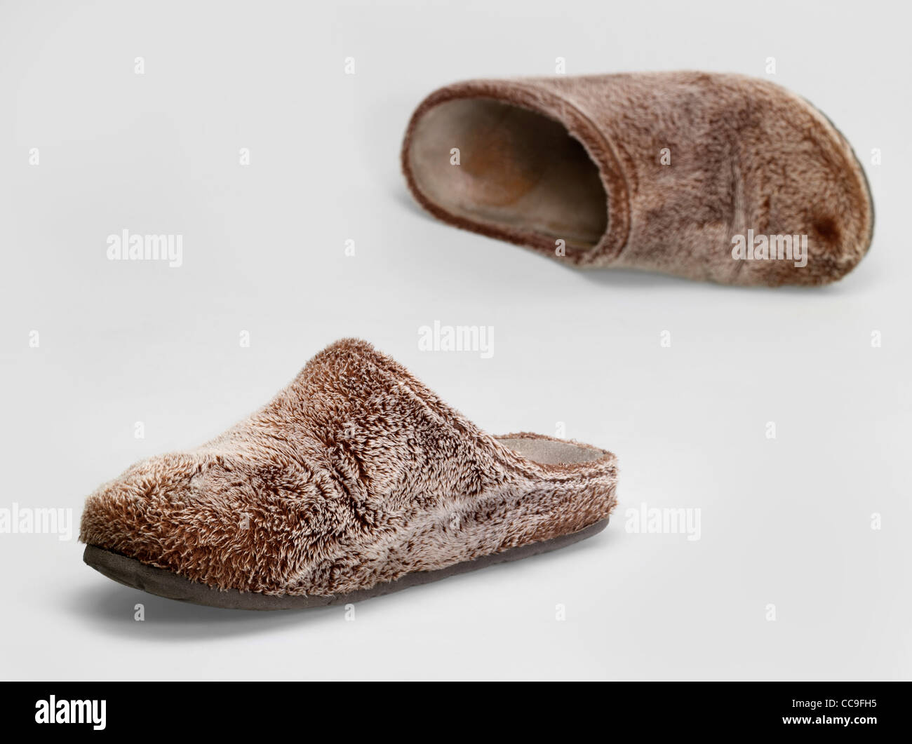 a pair of brown fluffy slippers in light grey back Stock Photo