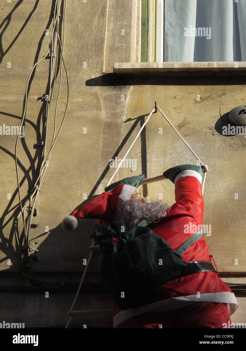 father christmas climbing house roof to deliver presents Stock Photo