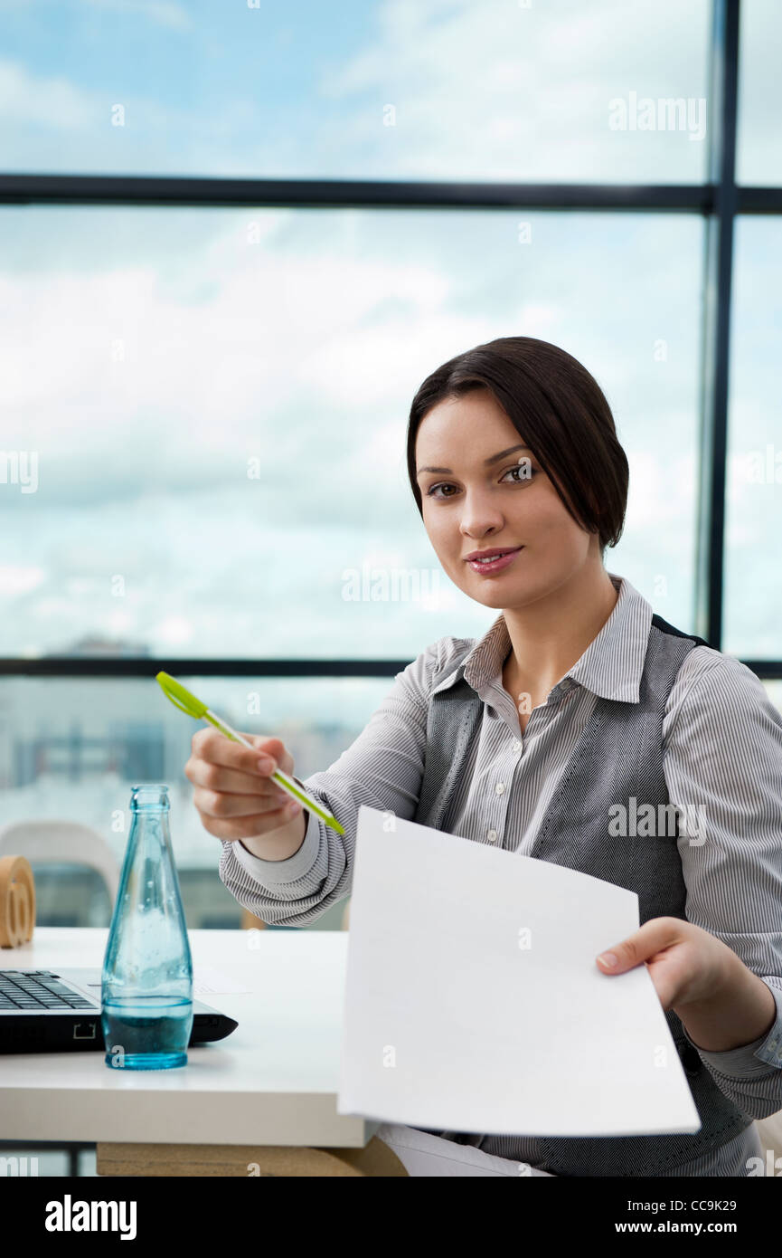 Portrait of a happy young agent giving pen and blank agreement to ...