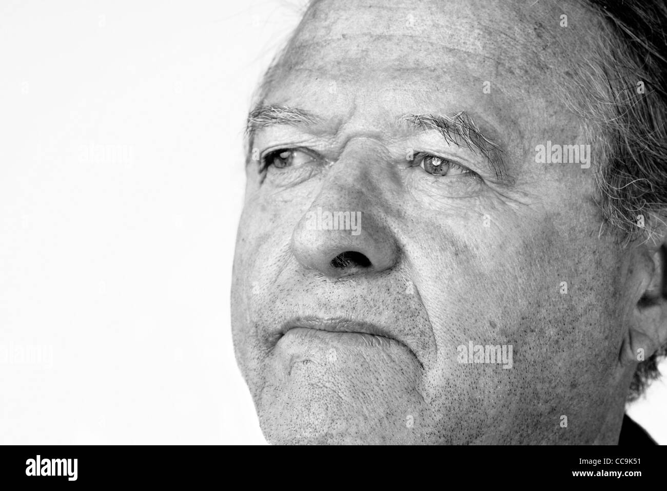 Black and white portrait of a senior man with pale eyes looking away with hint of a smile, great facial details, over white. Stock Photo