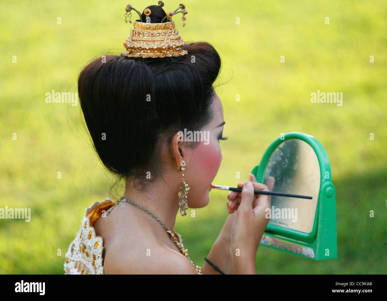 A young girl applying make-up before the Loi Krathong celebrations. Sukhothai Historical Park, Thailand. Stock Photo