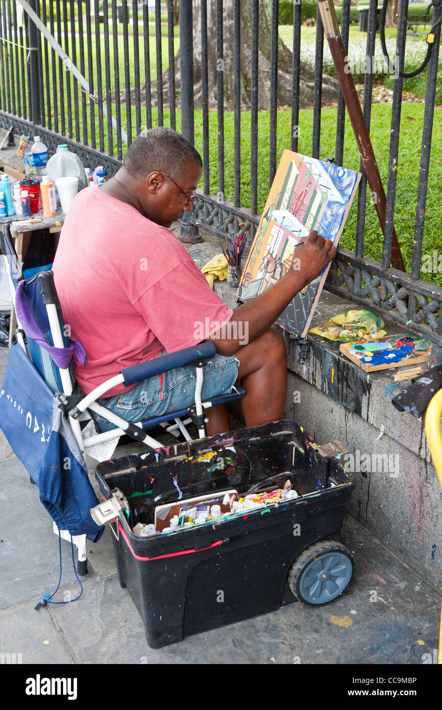 Black artist painting outdoors along St. Peter Street in the French Quarter of New Orleans, LA Stock Photo