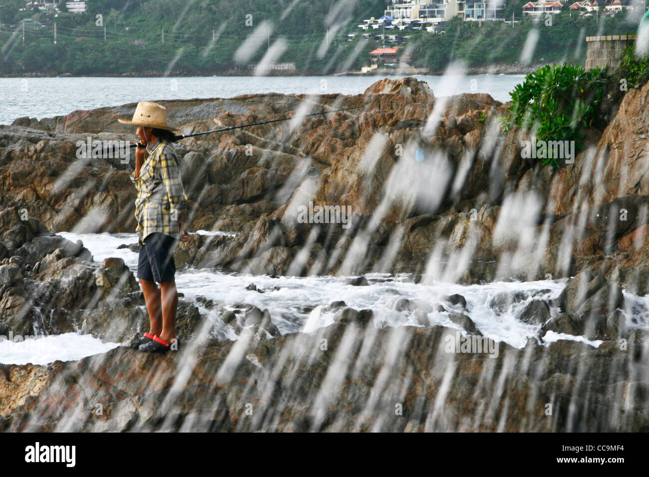 Fisherman on the rocks looking to the sea. Pukhet, Thailand. Stock Photo