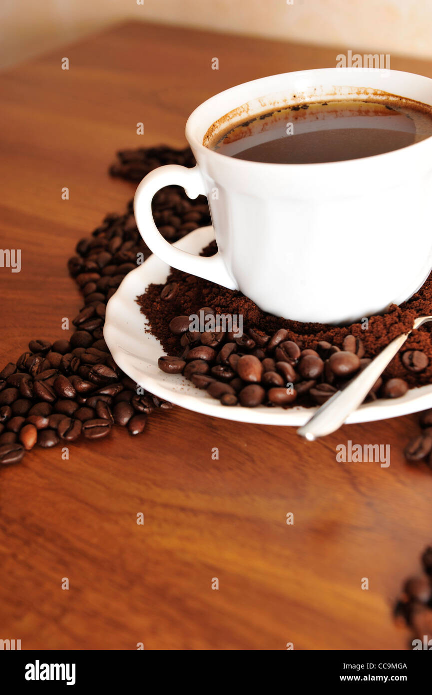 Dramatic photo of world map made of coffee beans. White cup with hot drink Stock Photo