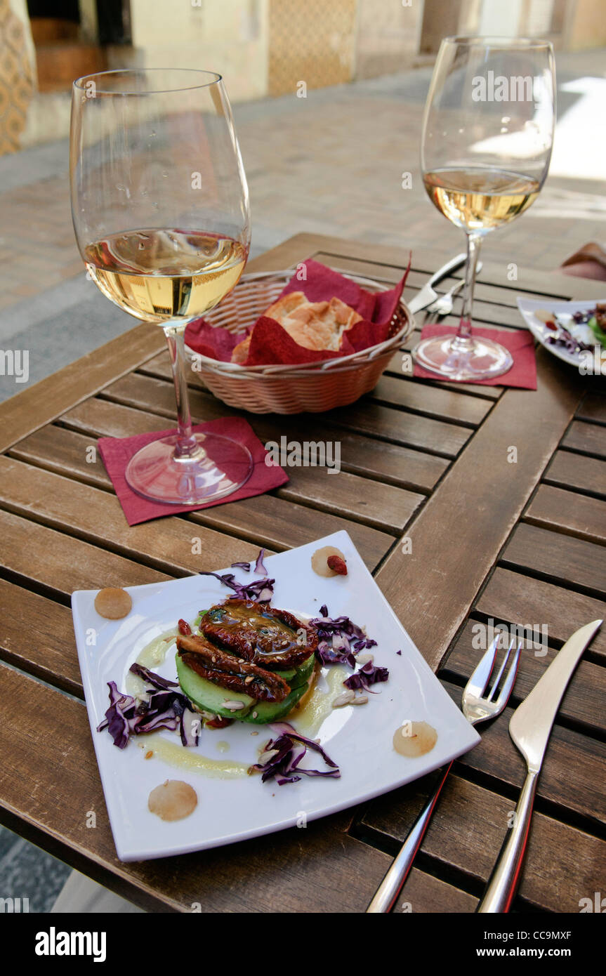 Tapas of dried Tomato and Avocado and two glasses of white wine on outside table in small alleyway in the old town of Benidorm, Stock Photo