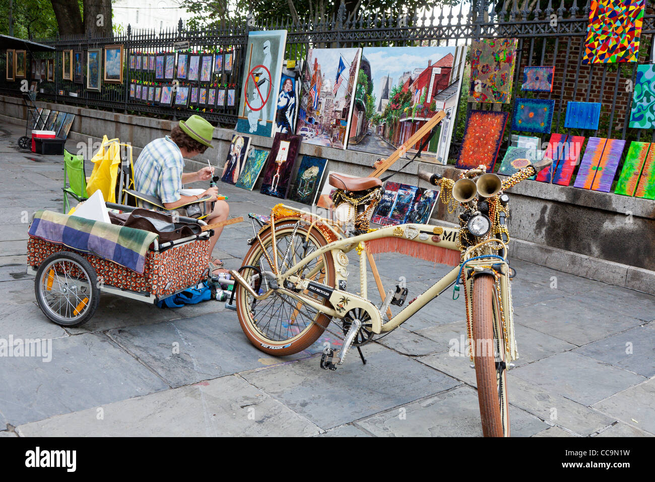 Artist with decorated bicycle creates paintings for sale along St. Peter Street in the French Quarter of New Orleans, LA Stock Photo