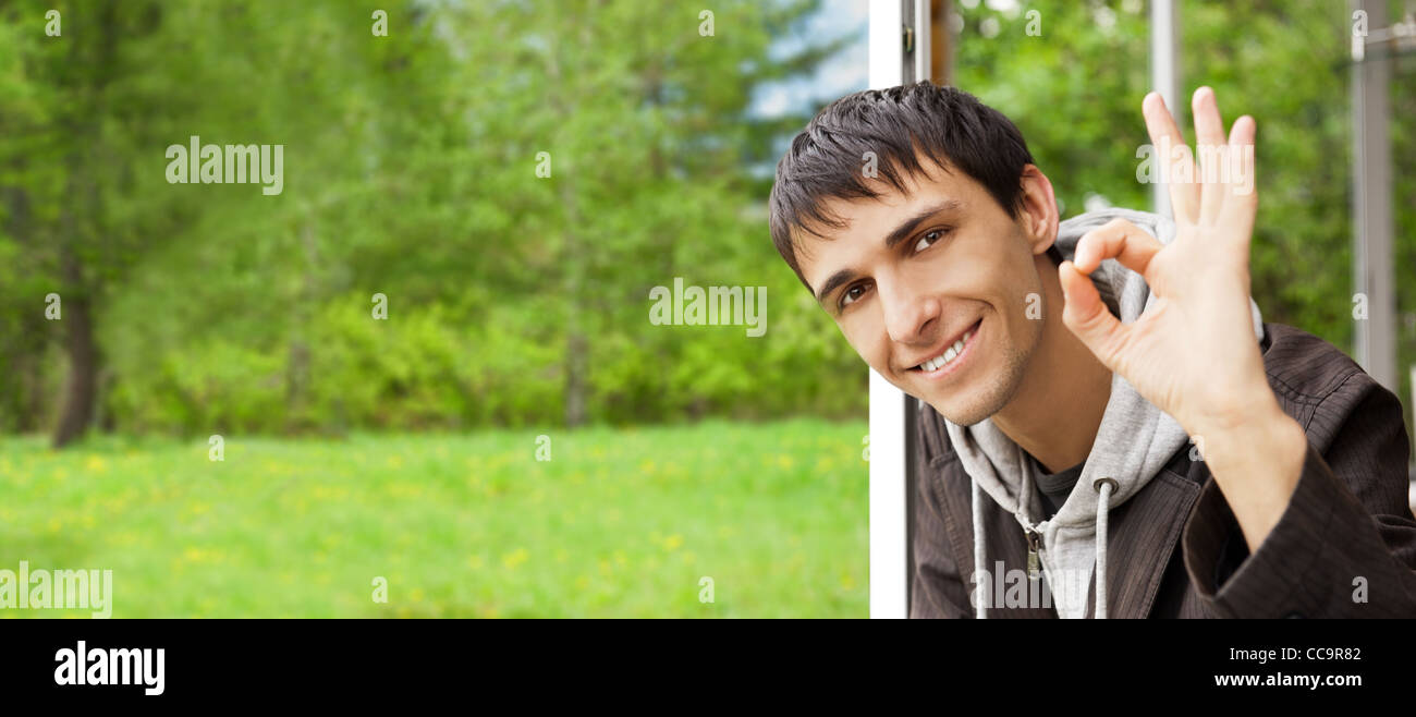 Satisfied smiling businessman standing in the green outdoors near window of his cottage Stock Photo