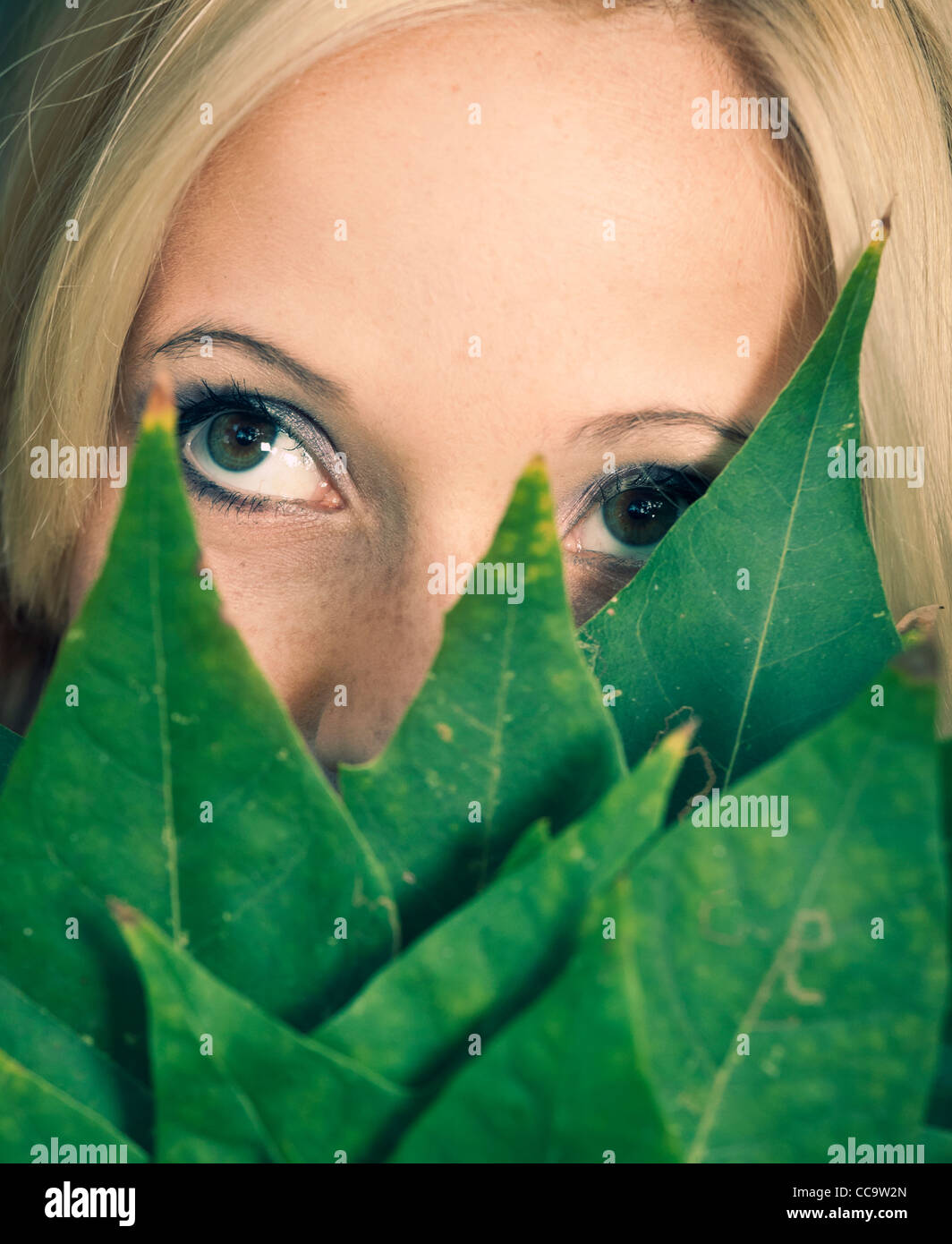 Close-up portrait of a beautiful girl holding leaves in front of face ...