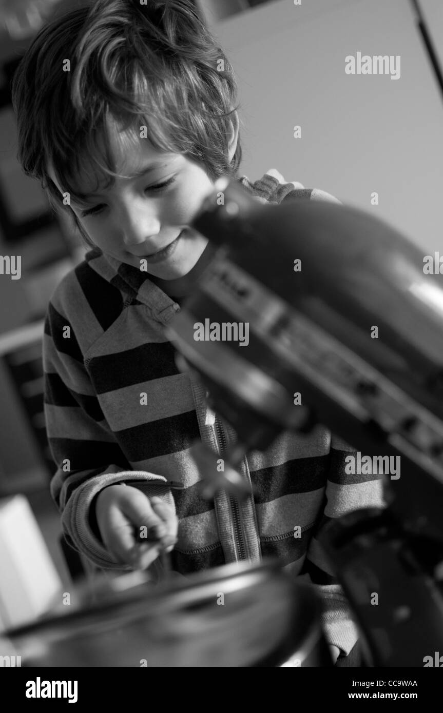 Young boy in the kitchen making a chocolate cake. Stock Photo