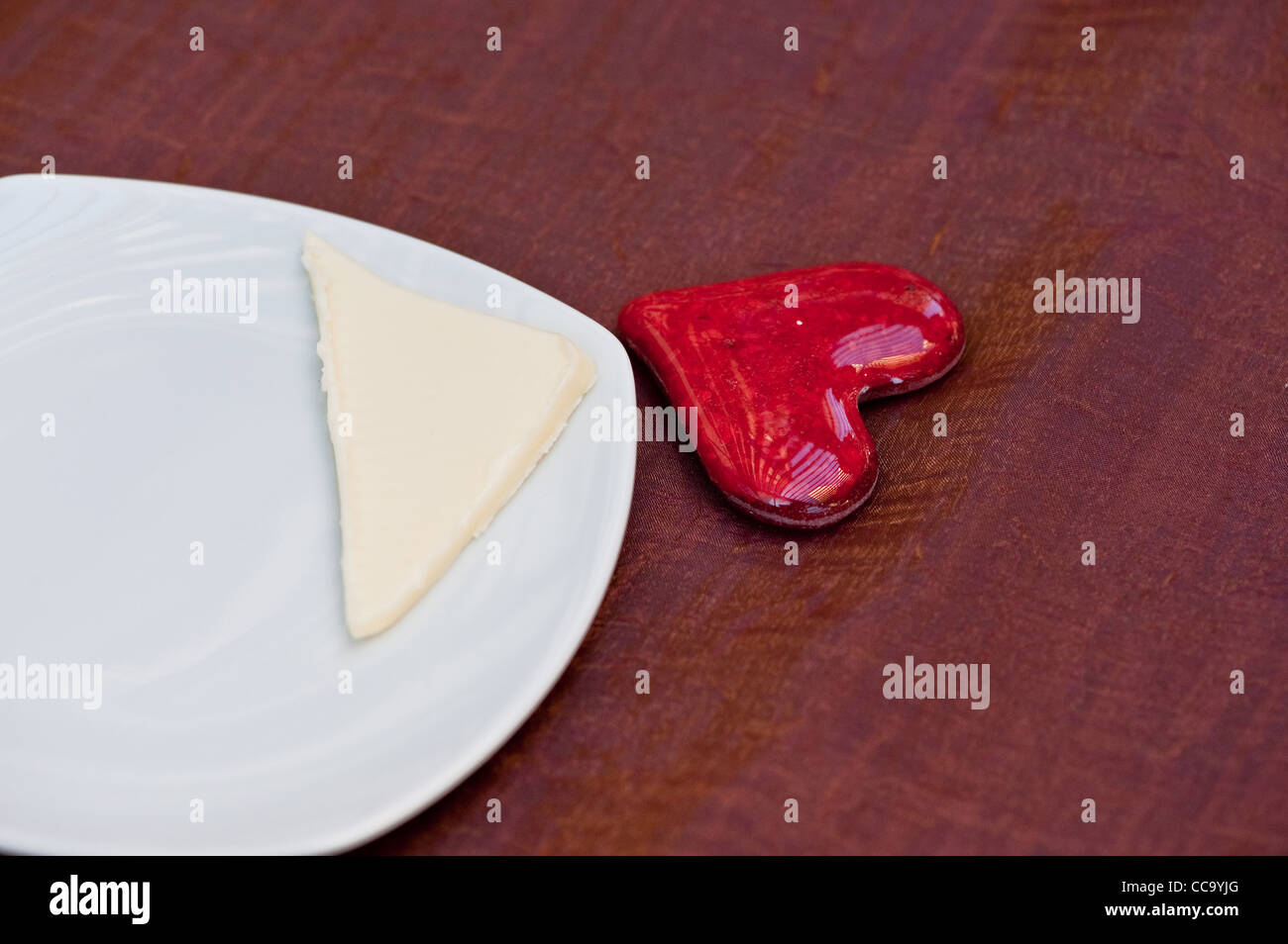 A red glass heart next to a plate Stock Photo