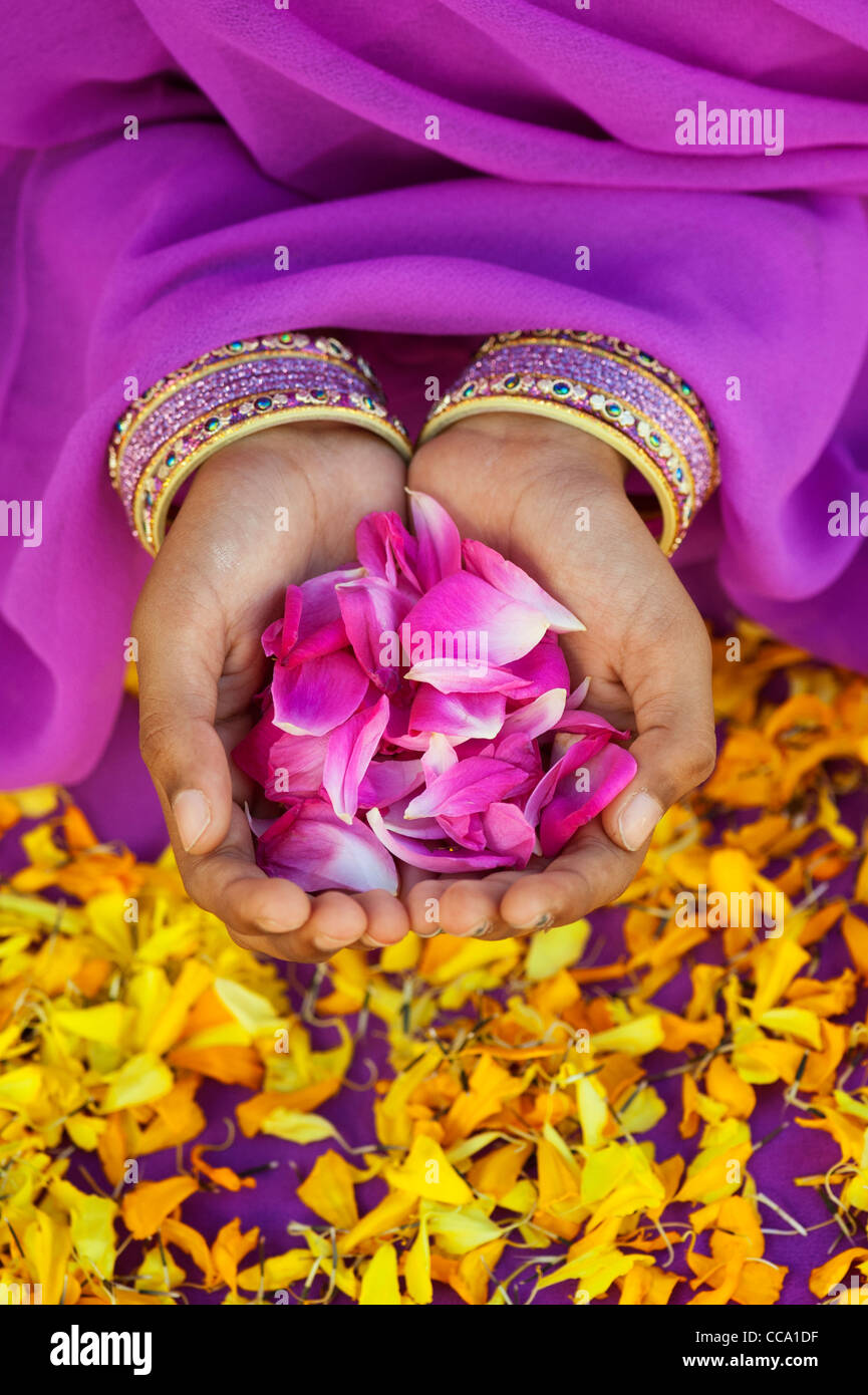 Indian girls hands holding rose petals surrounded by marigold flower petals Stock Photo