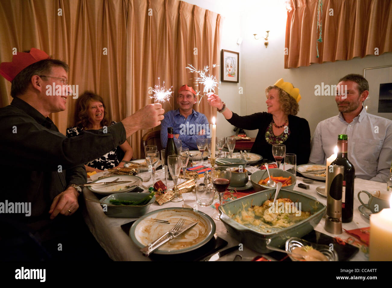 Five adults at the dinner table with indoor fireworks at a dinner party for New Years eve celebrations at home, UK Stock Photo