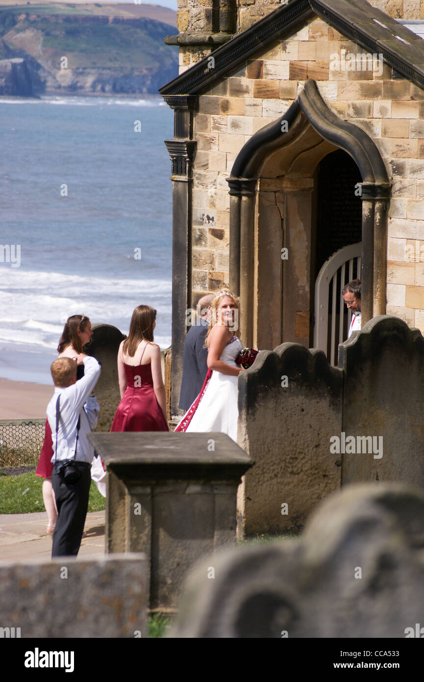 A smiling bride-to-be entering Church of St. Mary  above the harbour, Whitby, North Riding, Yorkshire, England Rear view. Stock Photo