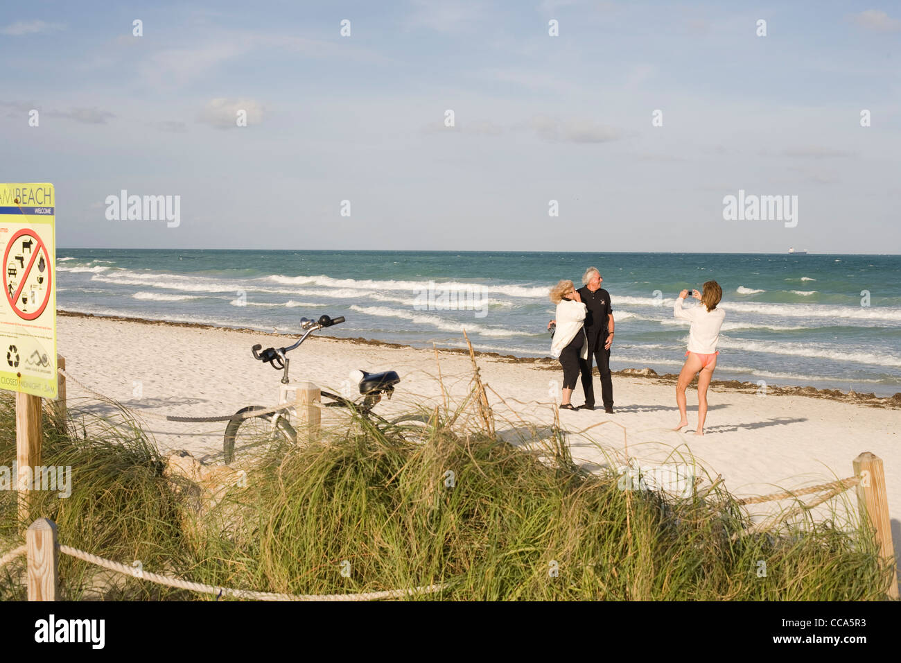 Woman in a bikini taking a photograph of a couple on South Beach Miami
