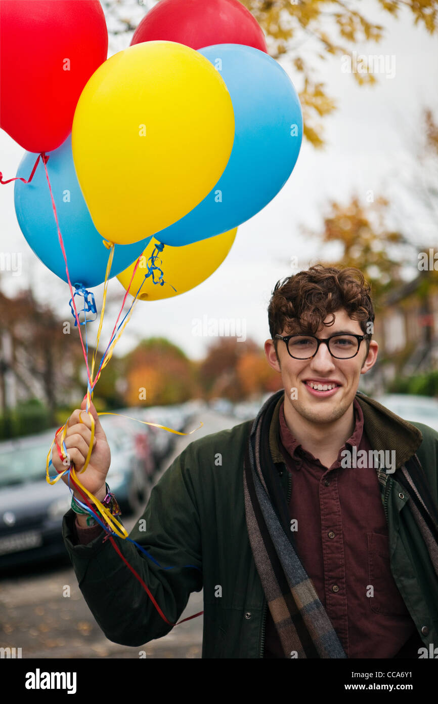 Young man holding colourful balloons, portrait Stock Photo Alamy