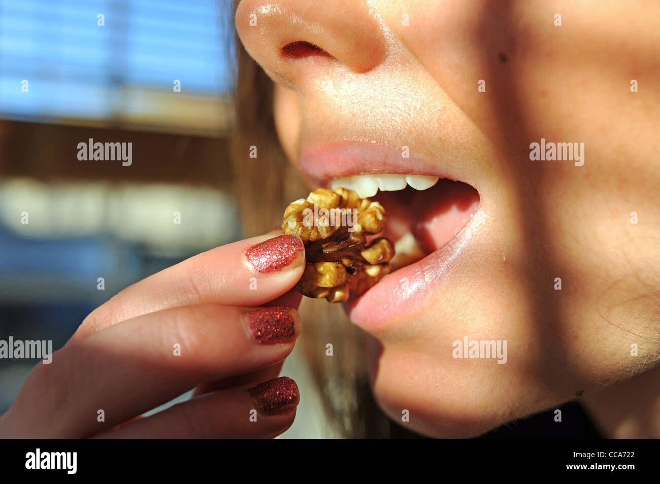 Healthy eating - Young woman biting into a walnut Stock Photo