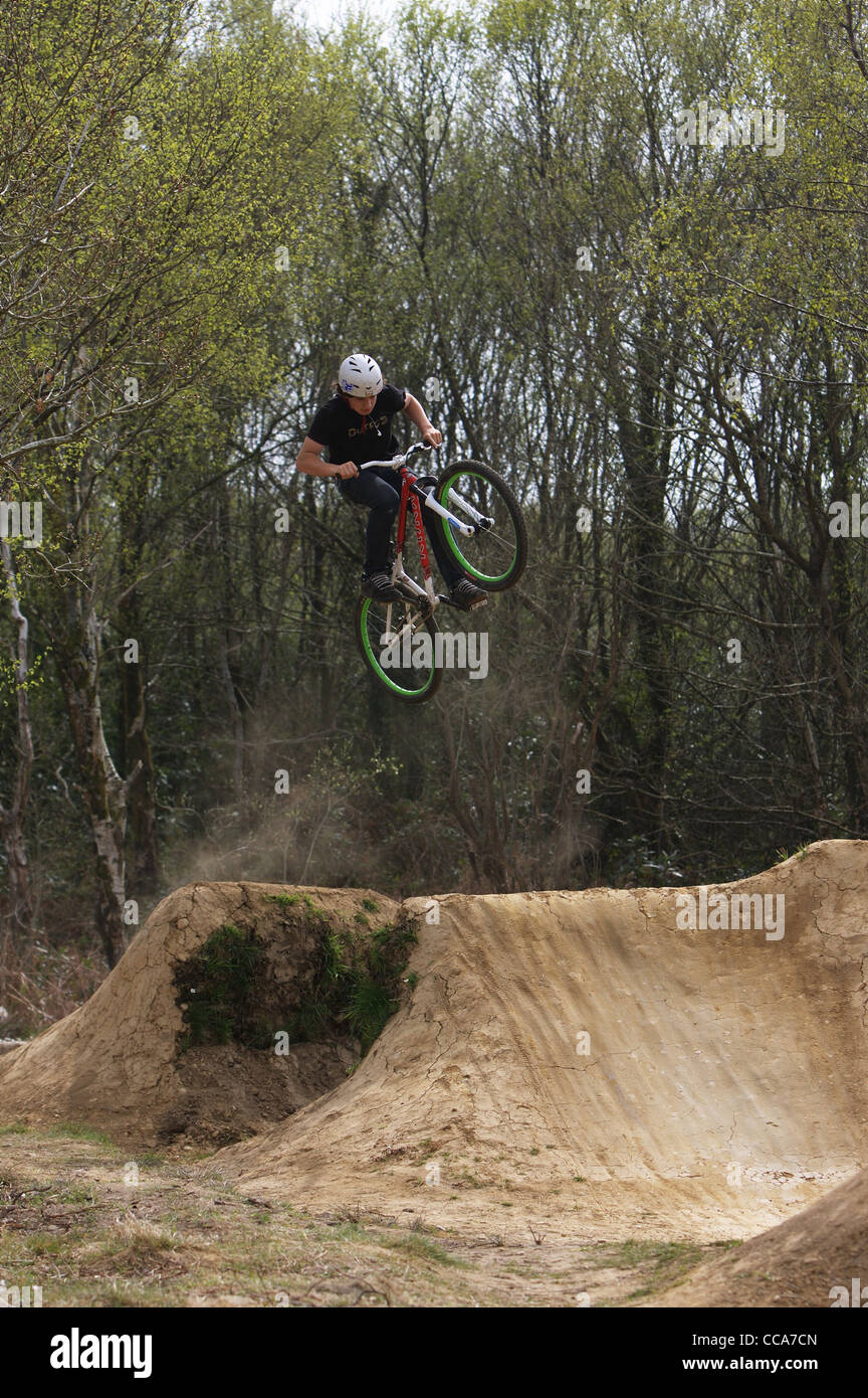 A mountain biker riding large dirt jumps in Swansea, South Wales Stock