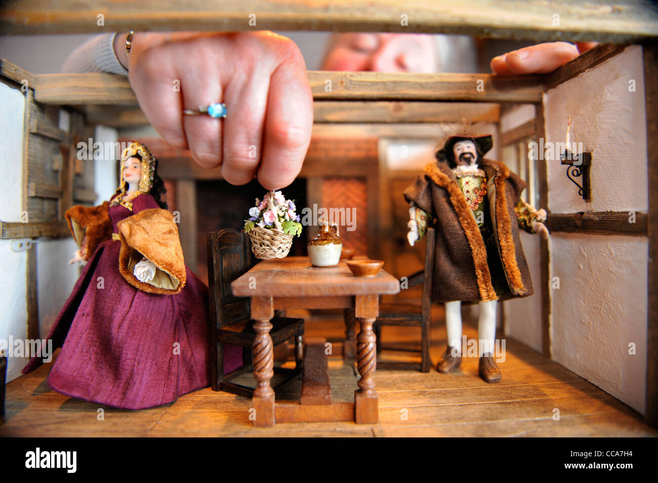 Kit Meggitt arranges items in her Tudor Aristocrats Solar Room displayed at 'Miniatura' - the dolls house and miniature modellin Stock Photo